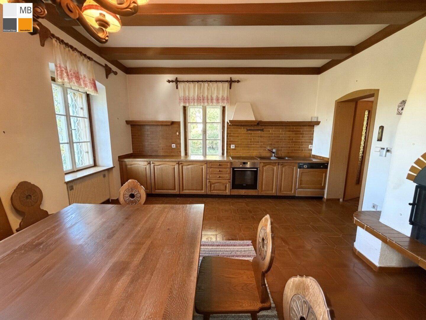 Funktionale Holzküche im Landhausstil mit integrierten Geräten und angrenzendem Essbereich.