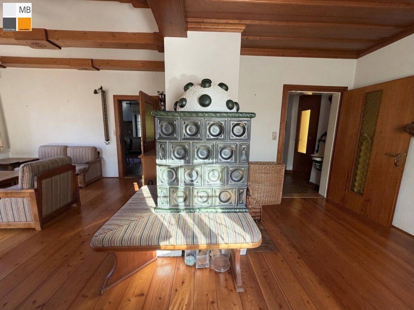 Blick auf den kunstvollen Kachelofen im Wohnbereich, umgeben von warmen Holzelementen und traditionellem Dekor.