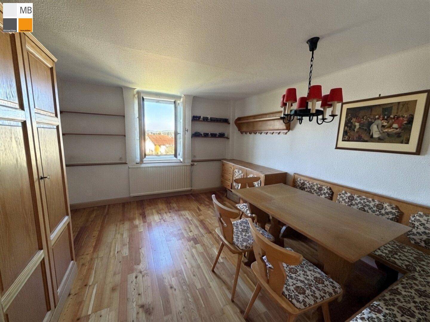 Rustikaler Essbereich mit Holztisch und Eckbank, umgeben von Holzmöbeln und Dielenboden.