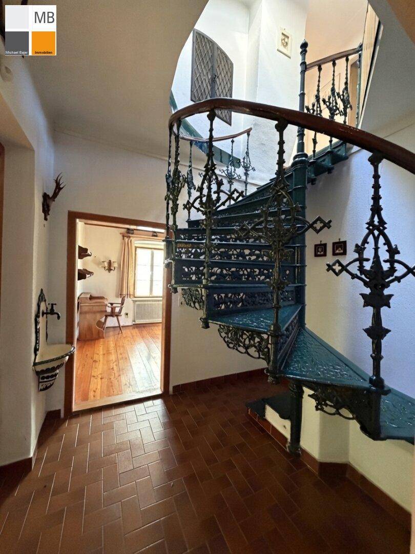 Elegantes Treppenhaus mit kunstvollem schmiedeeisernem Geländer und Terrakottafliesen.