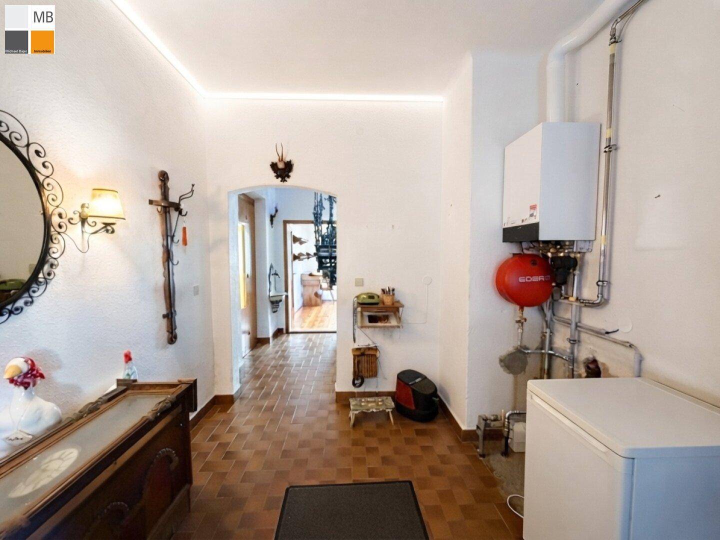 Praktischer Hauswirtschaftsraum mit Heizungsanlage, Waschmaschine und Terrakottafliesen.