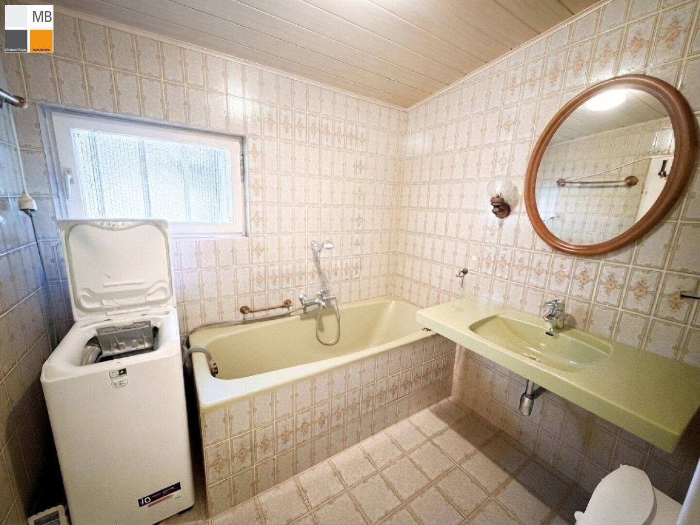Badezimmer im Stil der 80er Jahre mit Badewanne, Waschbecken und Waschmaschine.
