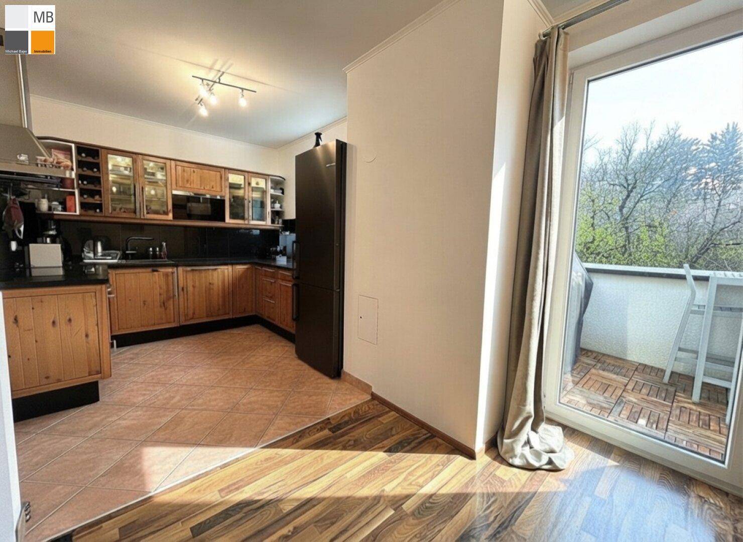 Wohnbereich mit Holzboden und direktem Zugang zum Balkon, neben der Küche.