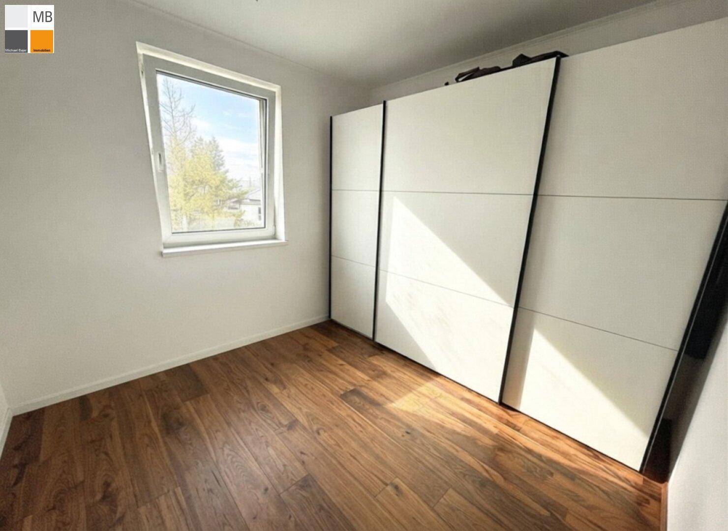 Schlafzimmer mit Holzboden und einem großen Schrank, der viel Stauraum bietet.