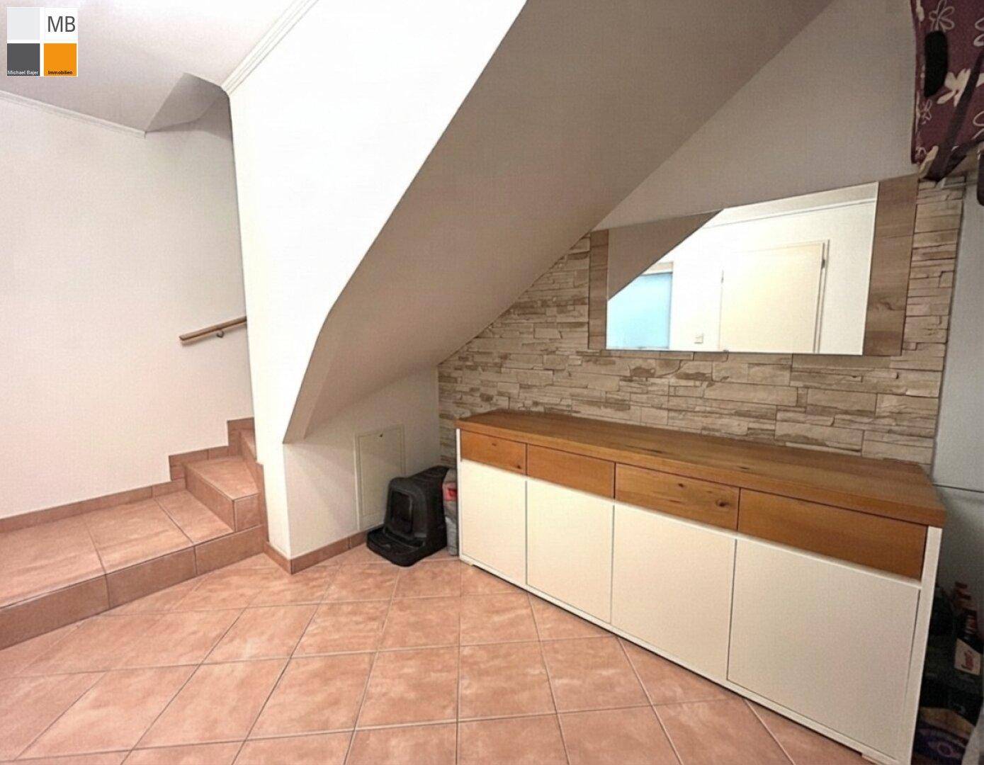 Eingangsbereich unter der Treppe mit Sideboard und dekorativer Steinwand.