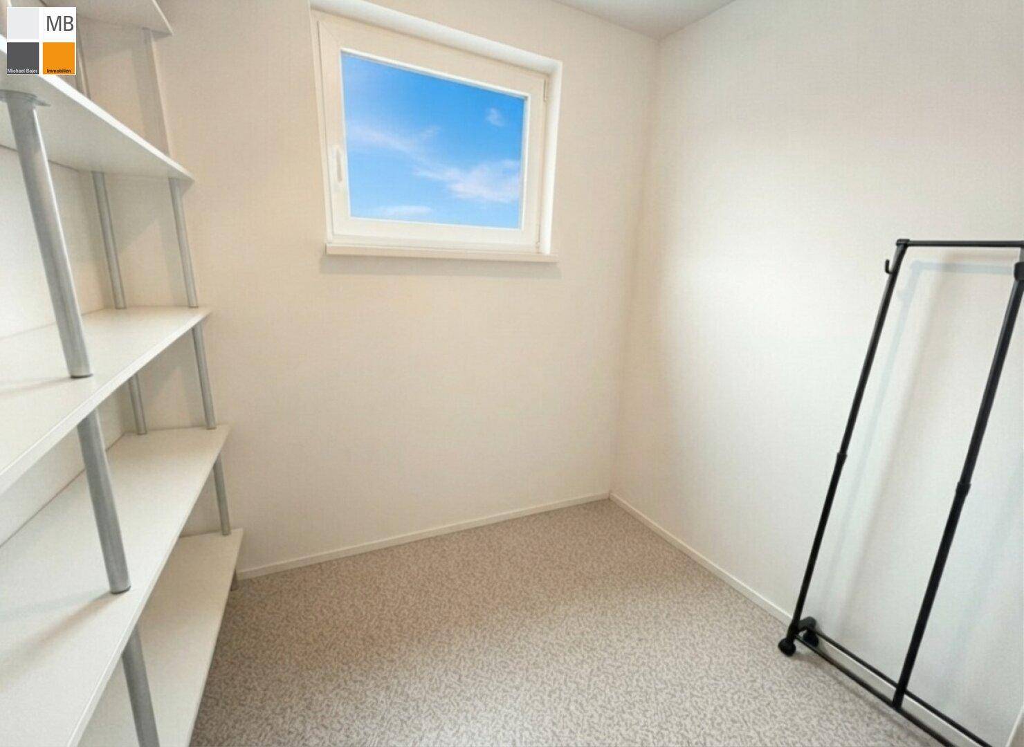Kleiner Abstellraum mit Teppichboden, Regal und Fenster für natürliche Belüftung.