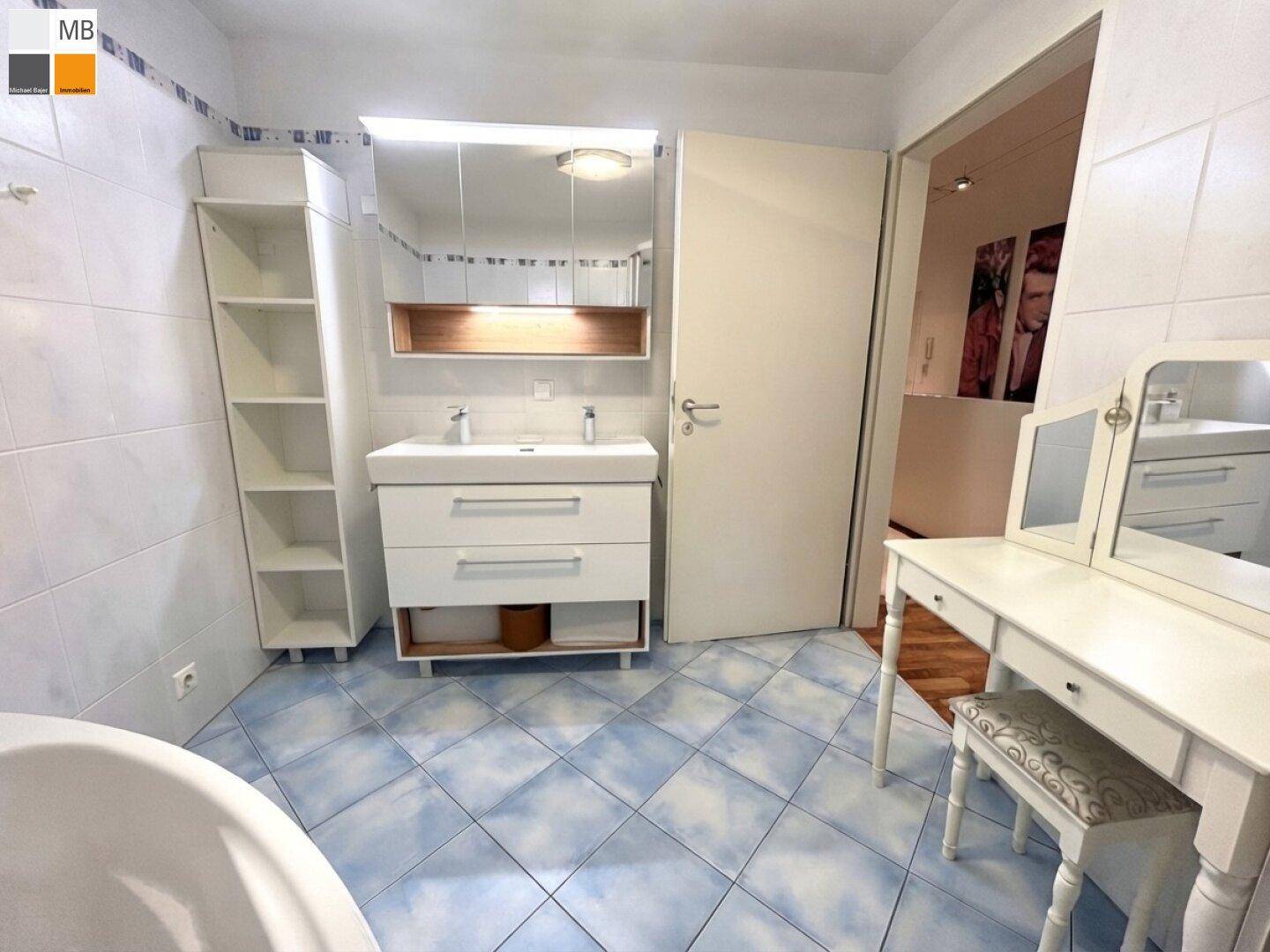 Geräumiges Badezimmer mit Doppelwaschbecken, Spiegel und Schminktisch.