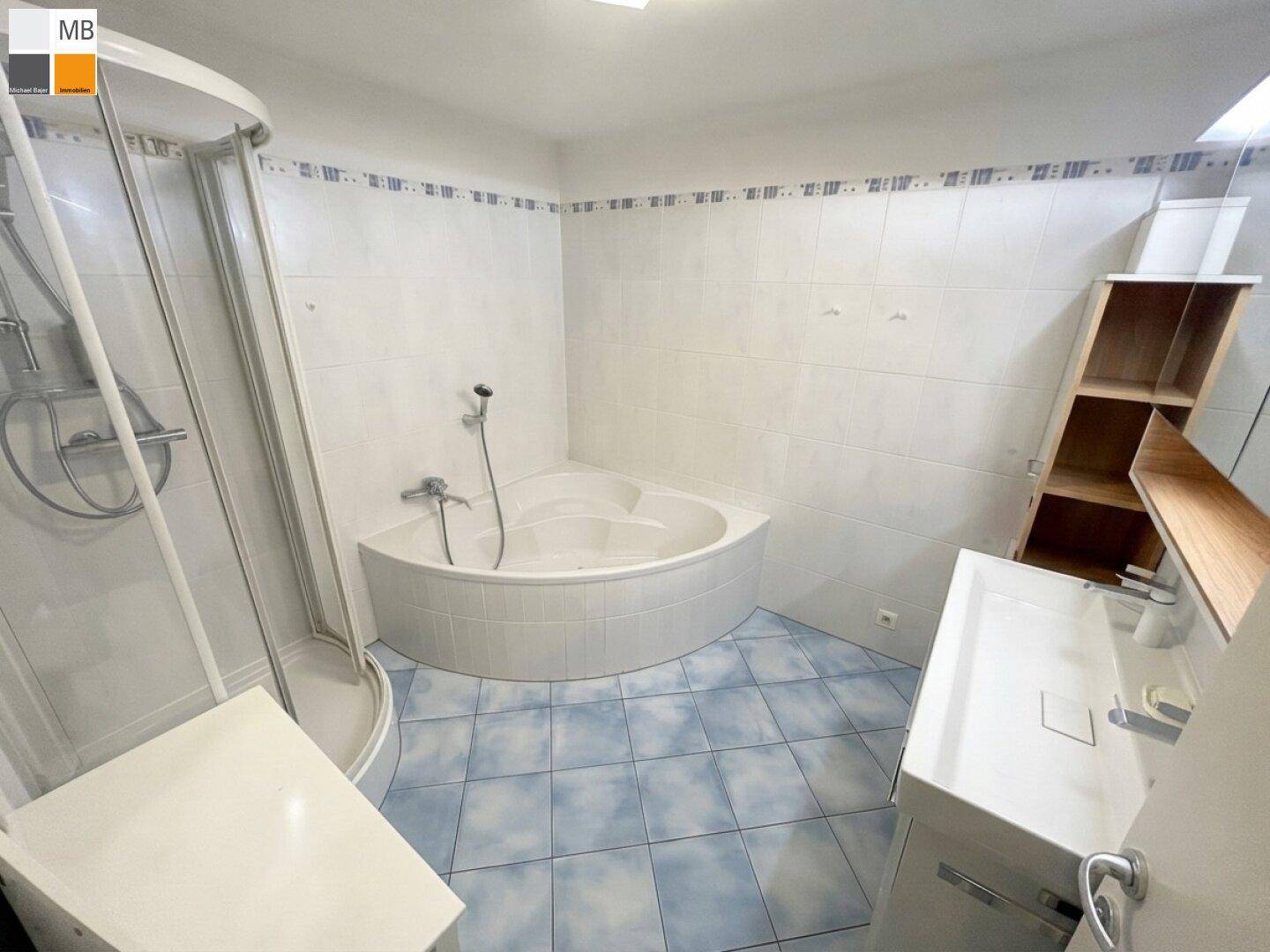 Badezimmer mit Eckbadewanne, Duschkabine und Waschbecken, alles in hellen Farben gehalten.
