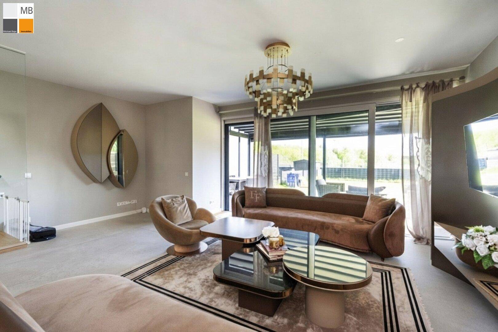 Helles Wohnzimmer mit eleganten Möbeln, großem Kronleuchter und Zugang zu einer Außenterrasse.