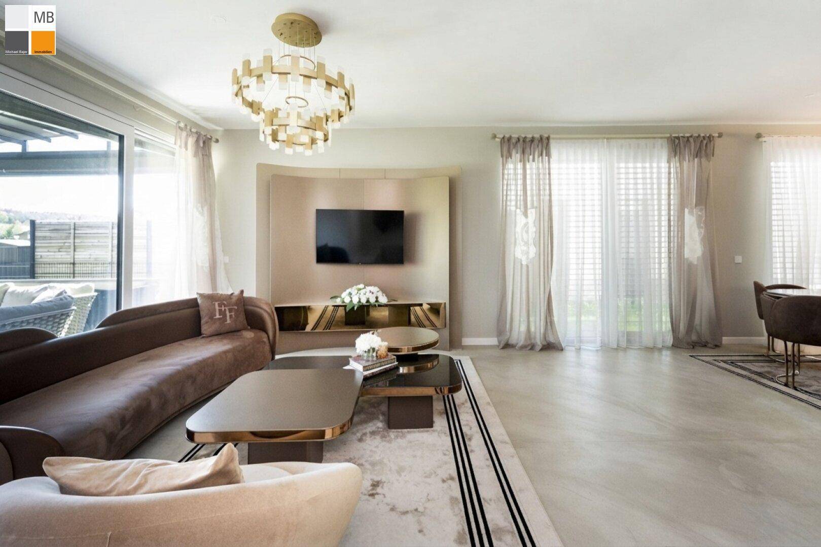 Geräumiges Wohnzimmer mit modernem TV-Bereich, bequemen Sofas und viel Tageslicht durch große Fenster.