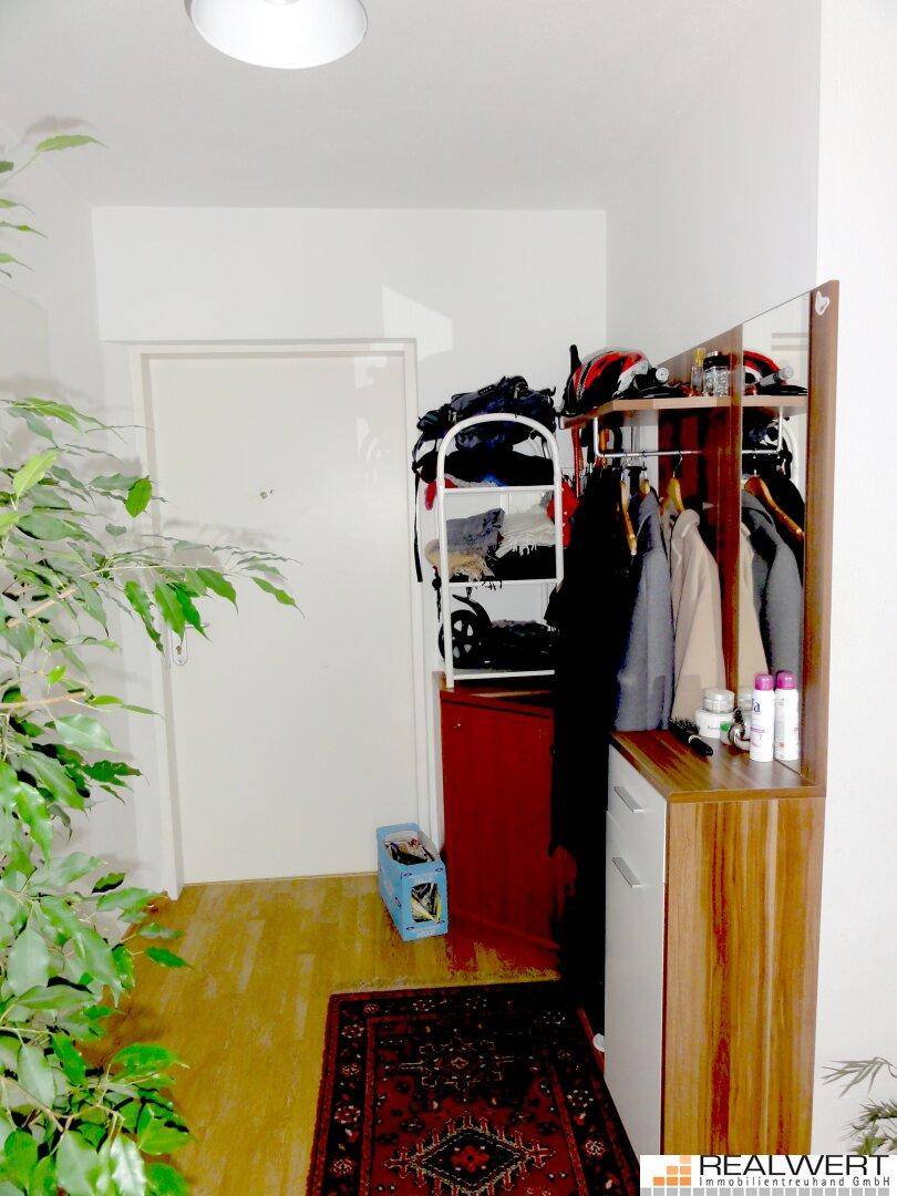Eingangsbereich mit Garderobe, Spiegel und Pflanzen, bietet praktischen Stauraum.
