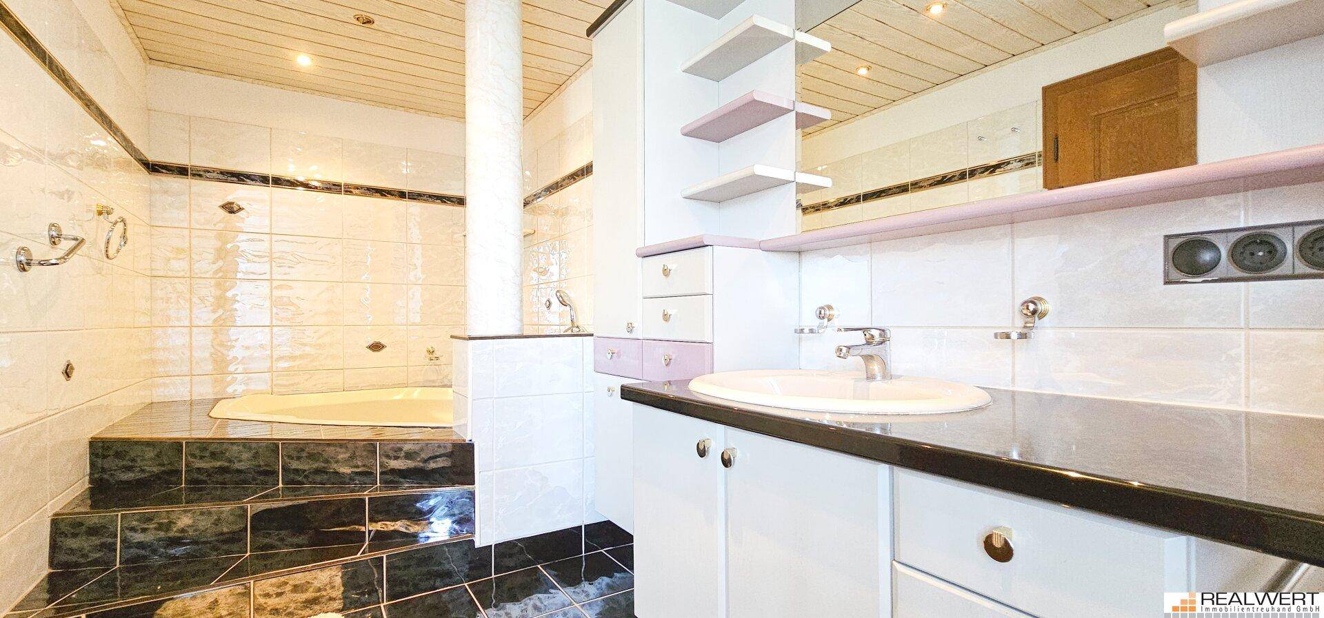 Badezimmer mit Fliesenboden, eingebauter Badewanne und einem modernen Waschtisch mit Unterschrank.