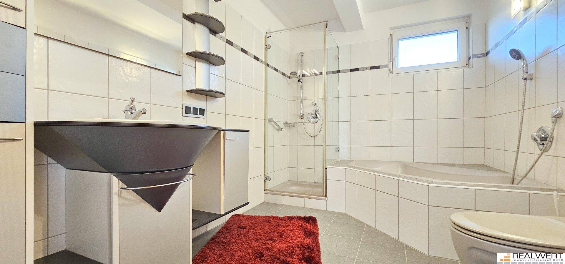 Modernes Badezimmer mit Dusche, Badewanne, Waschtisch und einem Fenster für Tageslicht.