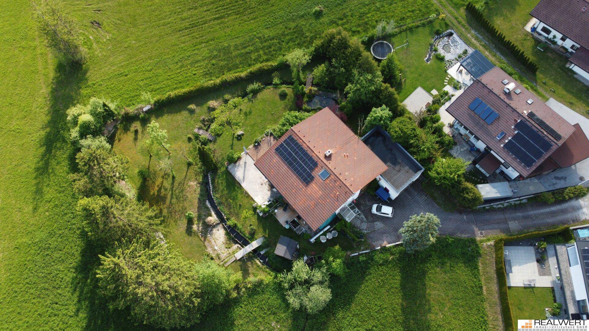 Senkrechte Luftaufnahme des Hauses mit Solaranlagen auf dem Dach und dem umliegenden Gartenbereich.
