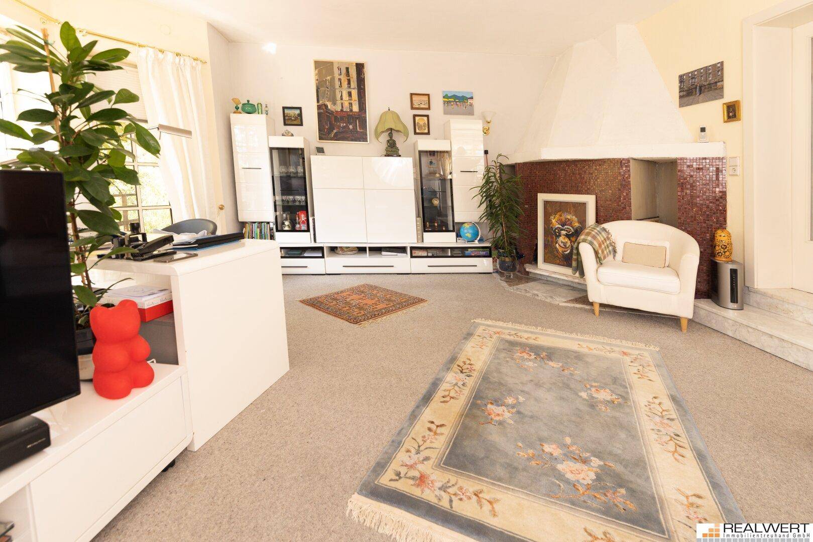 Geräumiges Wohnzimmer mit Kamin, weißer Medienkonsole und einem dekorativen Teppich.