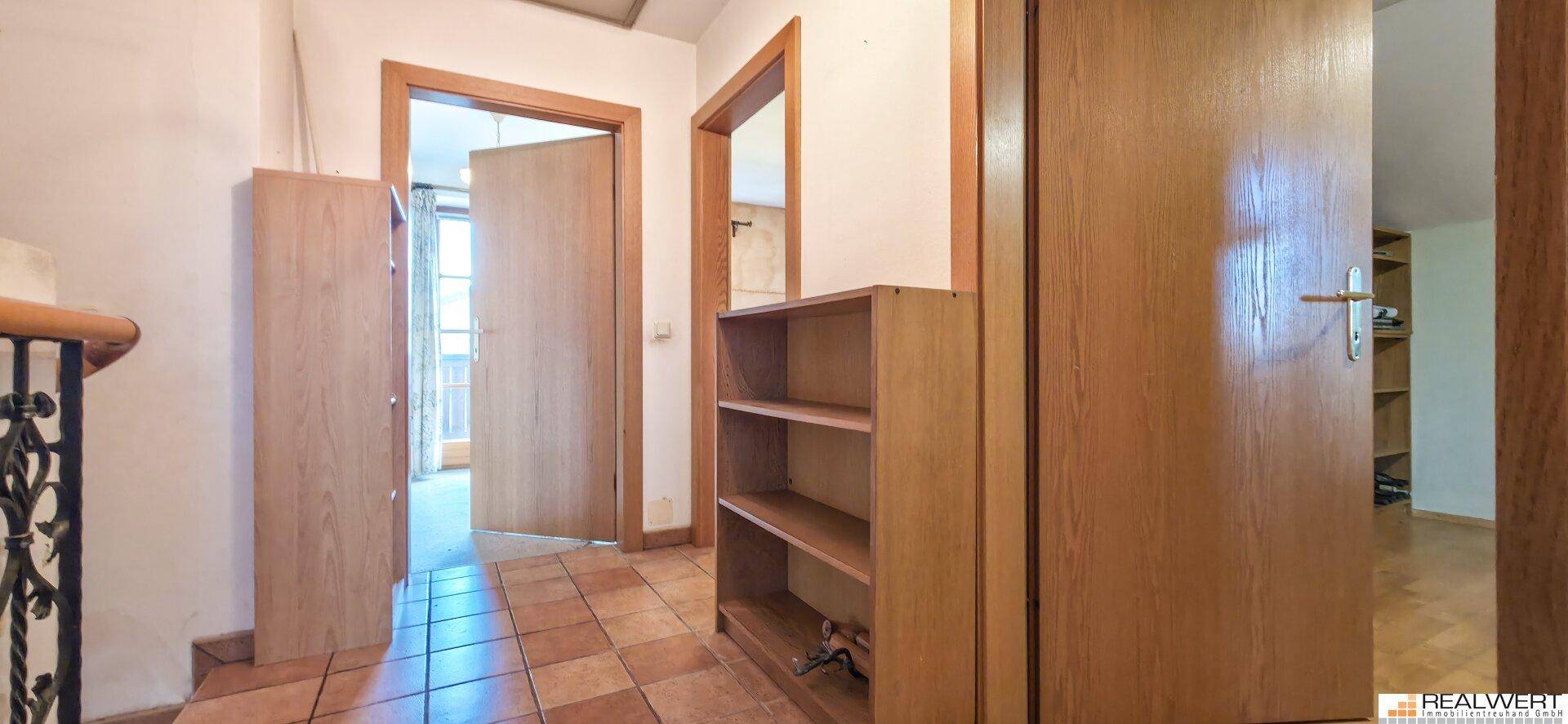 Heller Flur mit Fliesenboden und Holztüren, der zu weiteren Räumen führt.