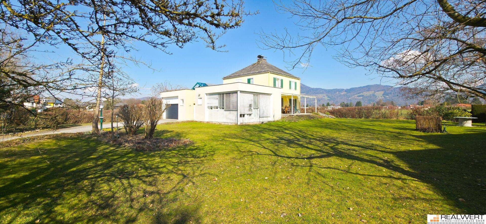 Sonniger Garten mit weitläufiger Rasenfläche und Blick auf das charmante Einfamilienhaus.