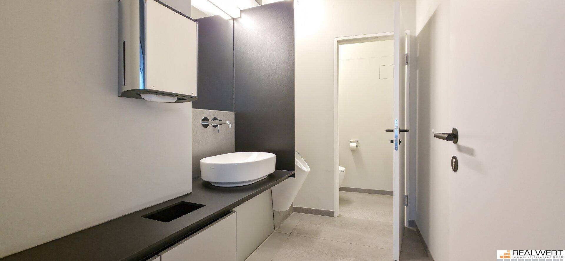 Modernes WC mit Aufsatzwaschbecken, Urinal und schlichtem Design.