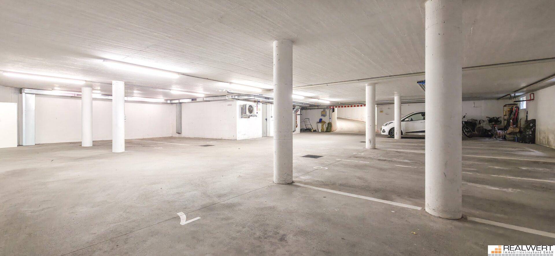 Geräumige Tiefgarage mit vielen Stellplätzen, Betonboden und Säulen.