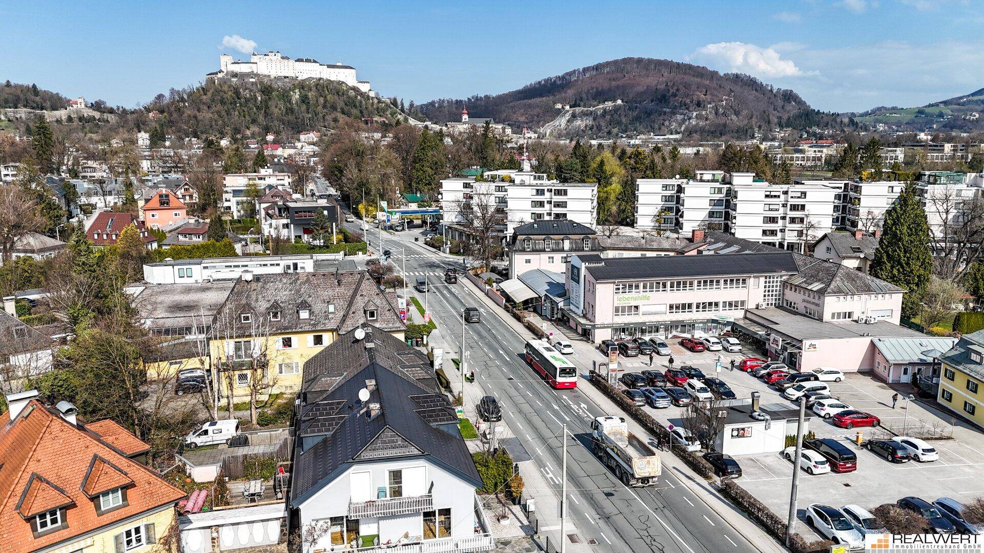 Weitläufige Luftaufnahme einer Stadt mit Gebäuden, Straßen und Bergen im Hintergrund.