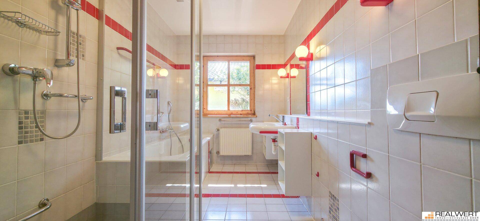 Badezimmer mit Dusche, Badewanne, Fenster und roten Akzentfliesen.