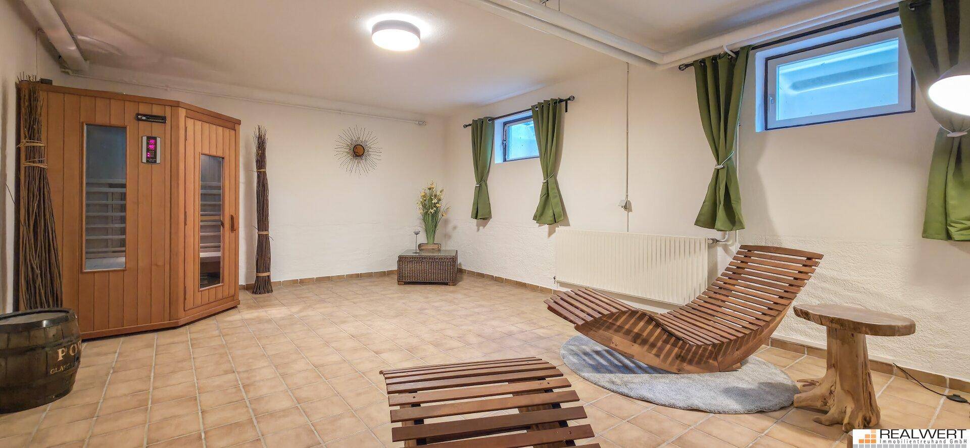 Entspannungsbereich im Untergeschoss mit einer Sauna, Fliesenboden und bequemen Liegemöbeln.