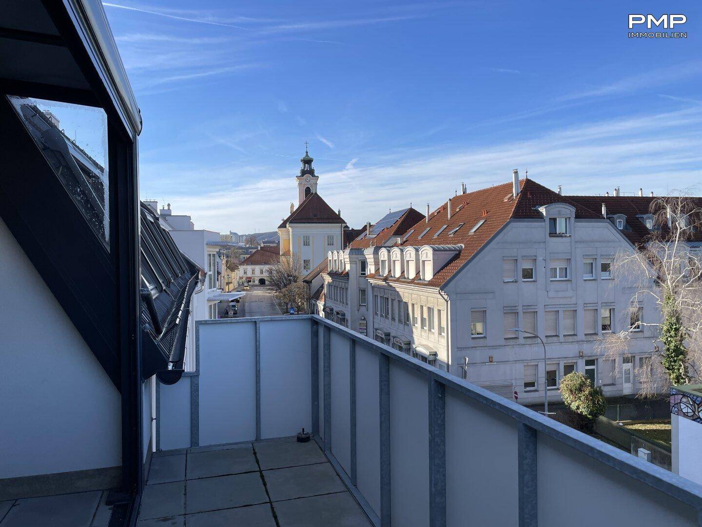 Weitläufiger Blick von der Dachterrasse über die Stadt mit historischen Gebäuden und Kirchturm.