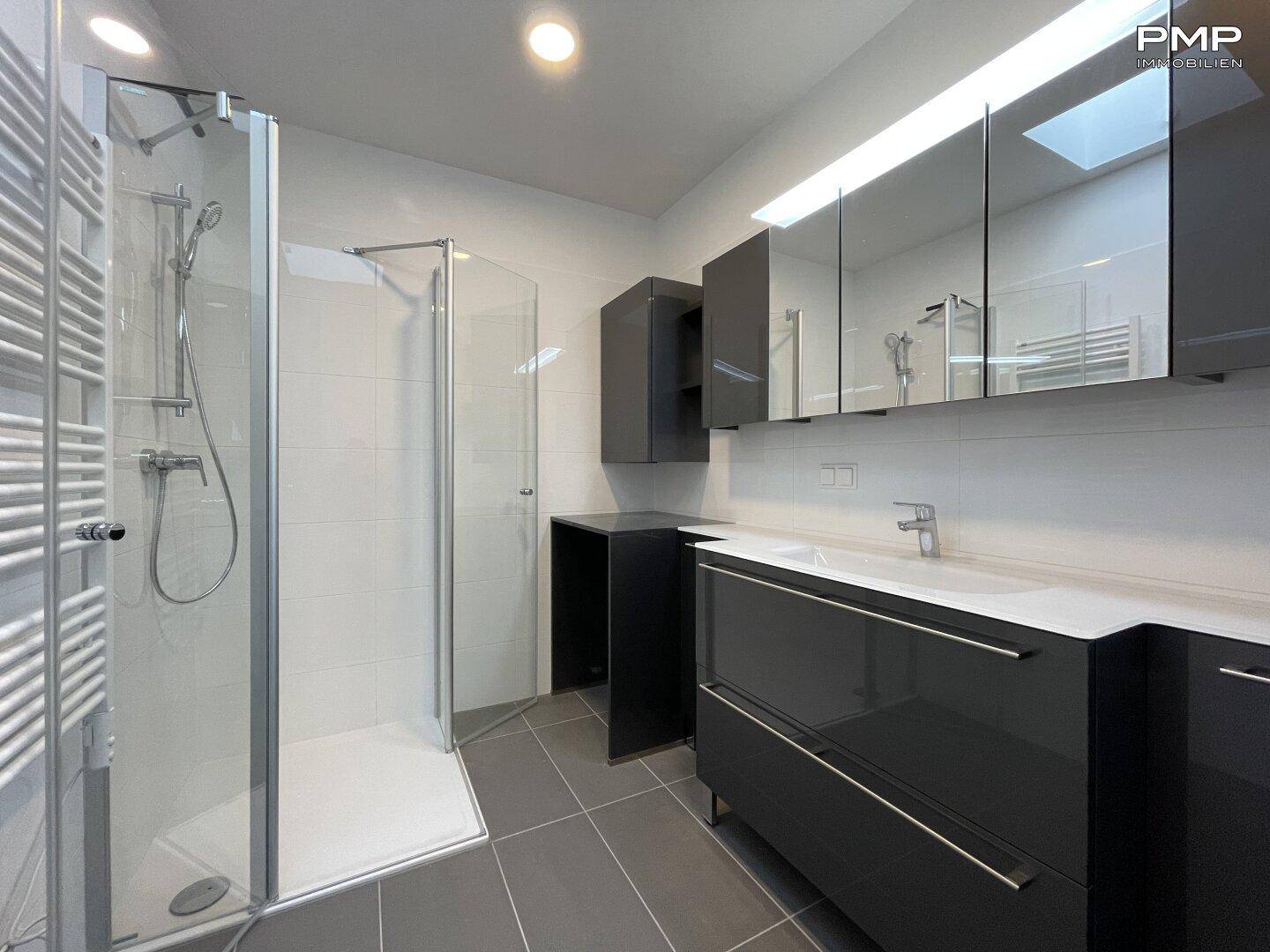 Elegantes Badezimmer mit Duschkabine, dunklen Möbeln und großem Waschbecken.