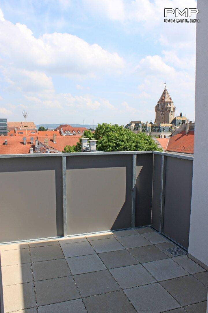 Balkon mit Fliesenboden und Blick auf die historische Stadtkulisse mit Kirchturm.