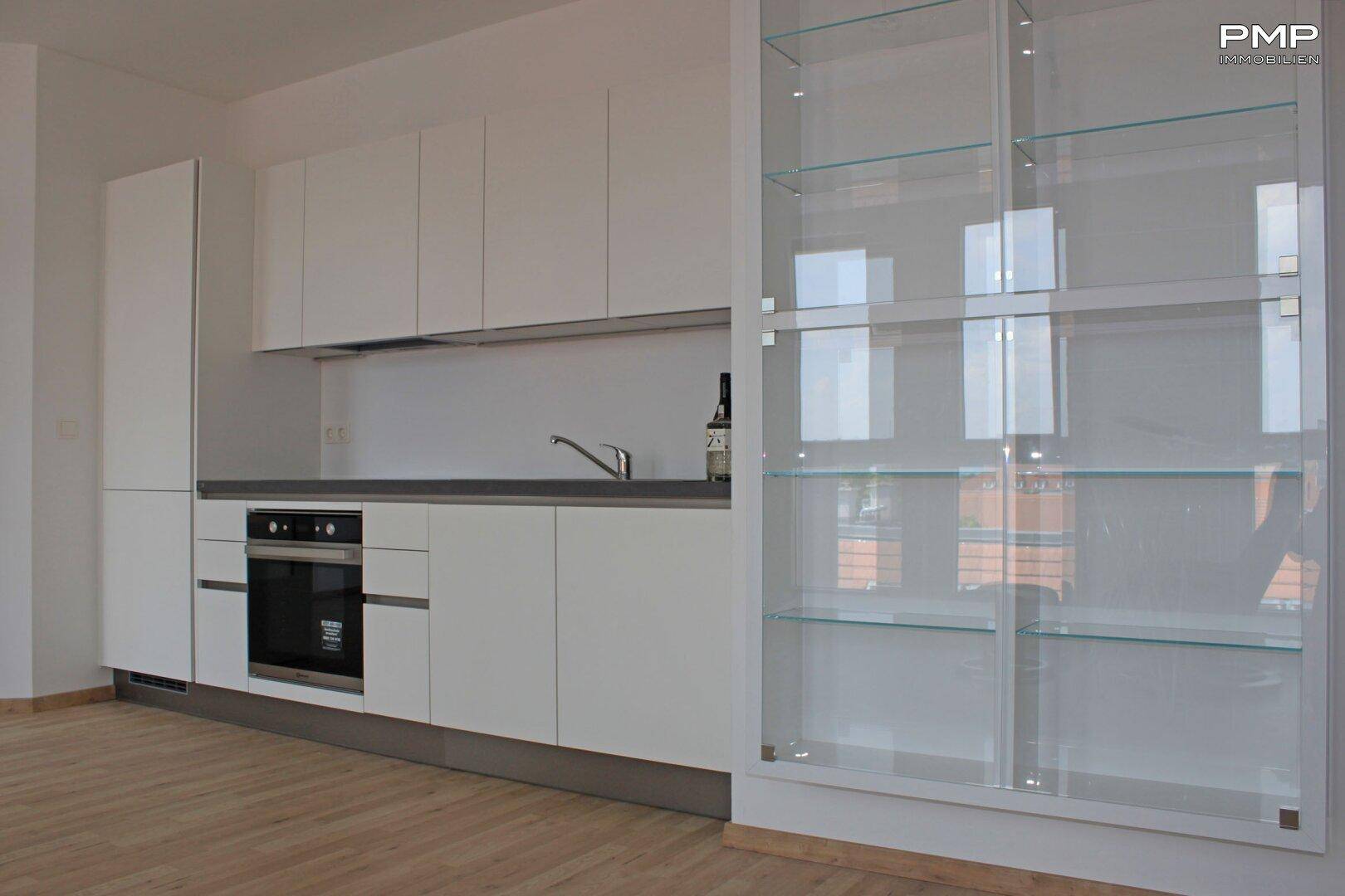 Moderne Einbauküche in Weiß mit integrierten Geräten und Holzfußboden.