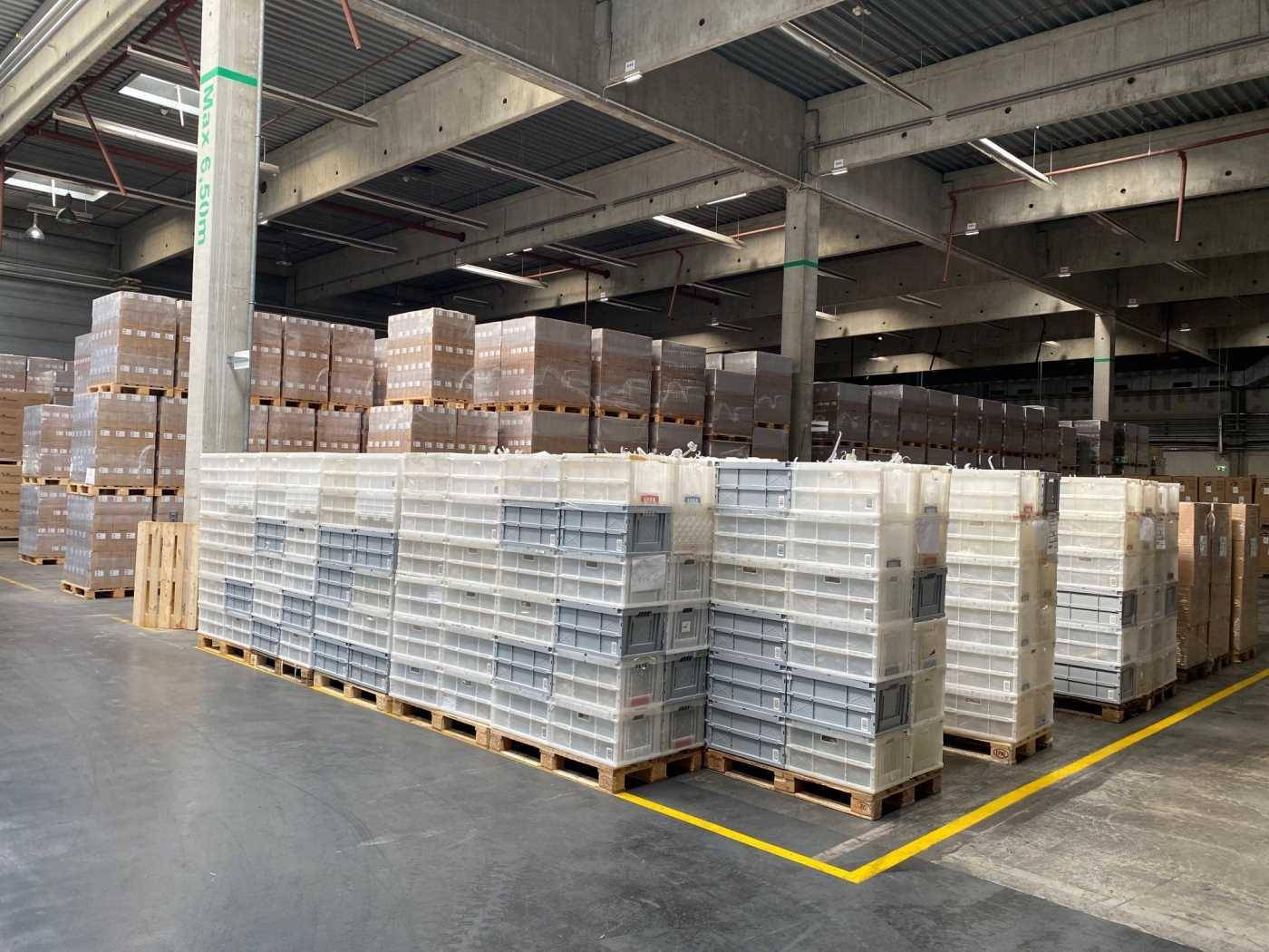Große Lagerhalle mit hohen Decken und zahlreichen gestapelten Waren auf Paletten.