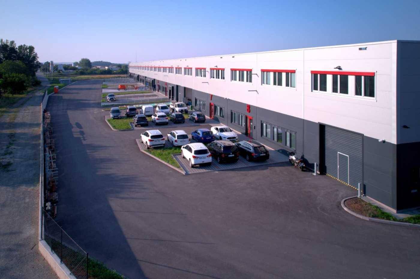 Großer Parkplatz neben dem modernen Lagergebäude mit zahlreichen Stellplätzen für Mitarbeiter und Besucher.
