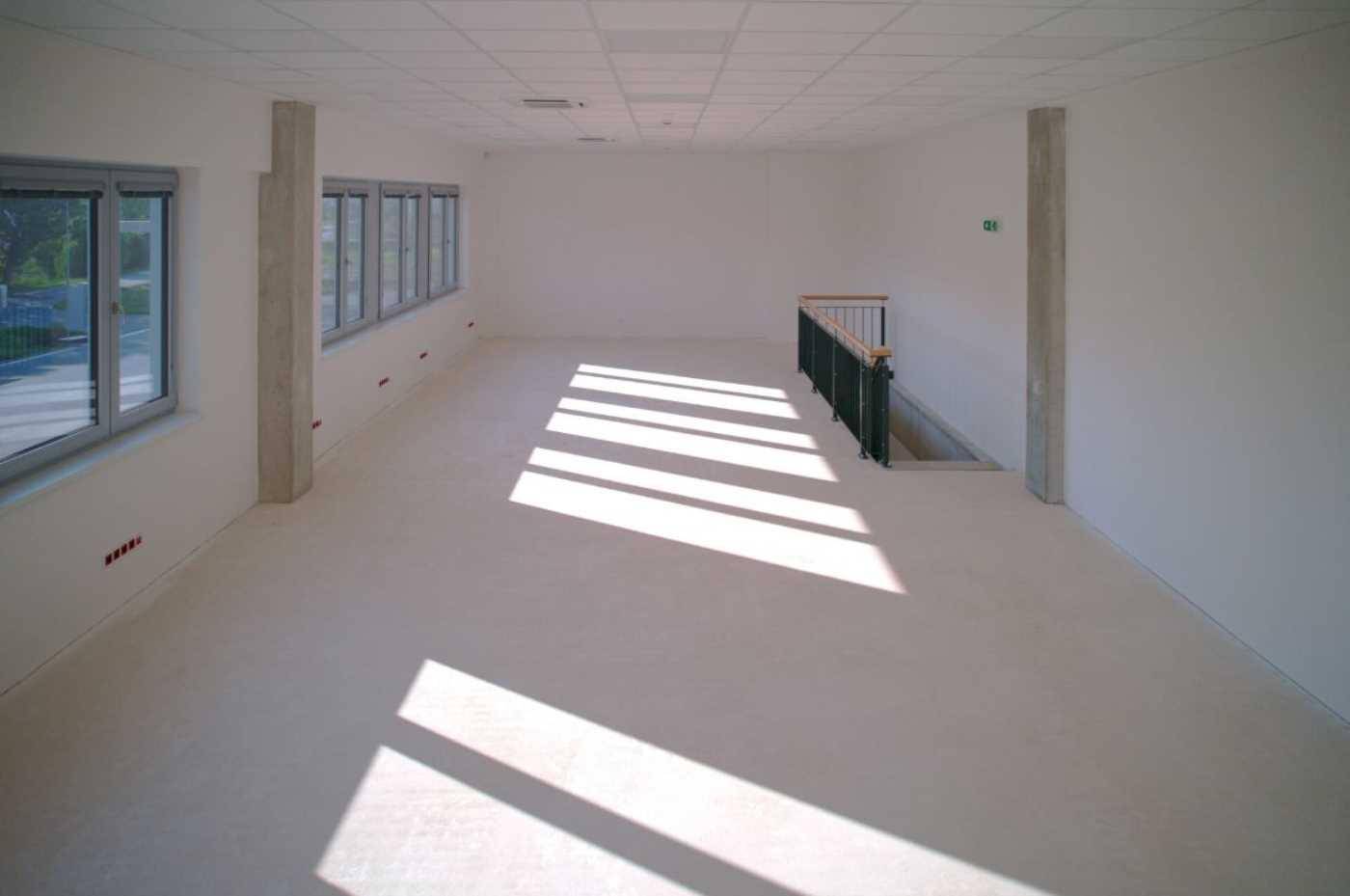 Heller, leerer Büroraum im Obergeschoss mit großen Fenstern und viel natürlichem Licht.