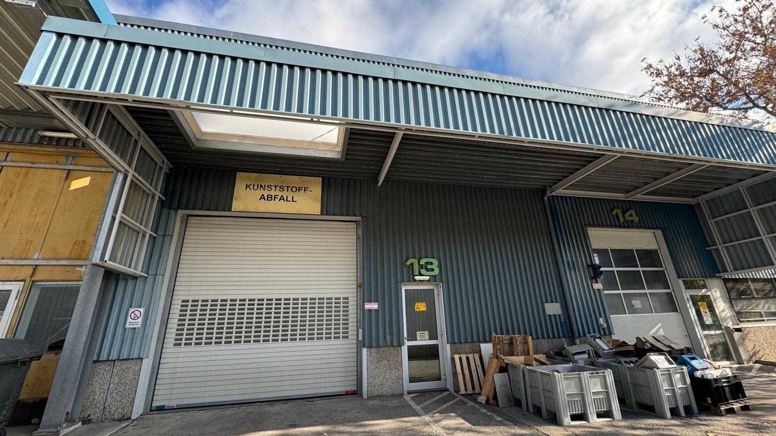 Industrielles Gebäude mit Rolltor und Überdachung, gekennzeichnet als Kunststoffabfall-Sammelstelle.