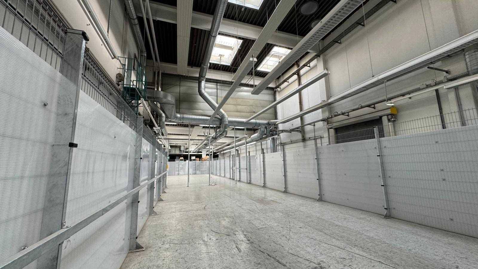 Große Lagerhalle mit hohen Decken, Oberlichtern und Metallwänden, die viel Platz bieten.