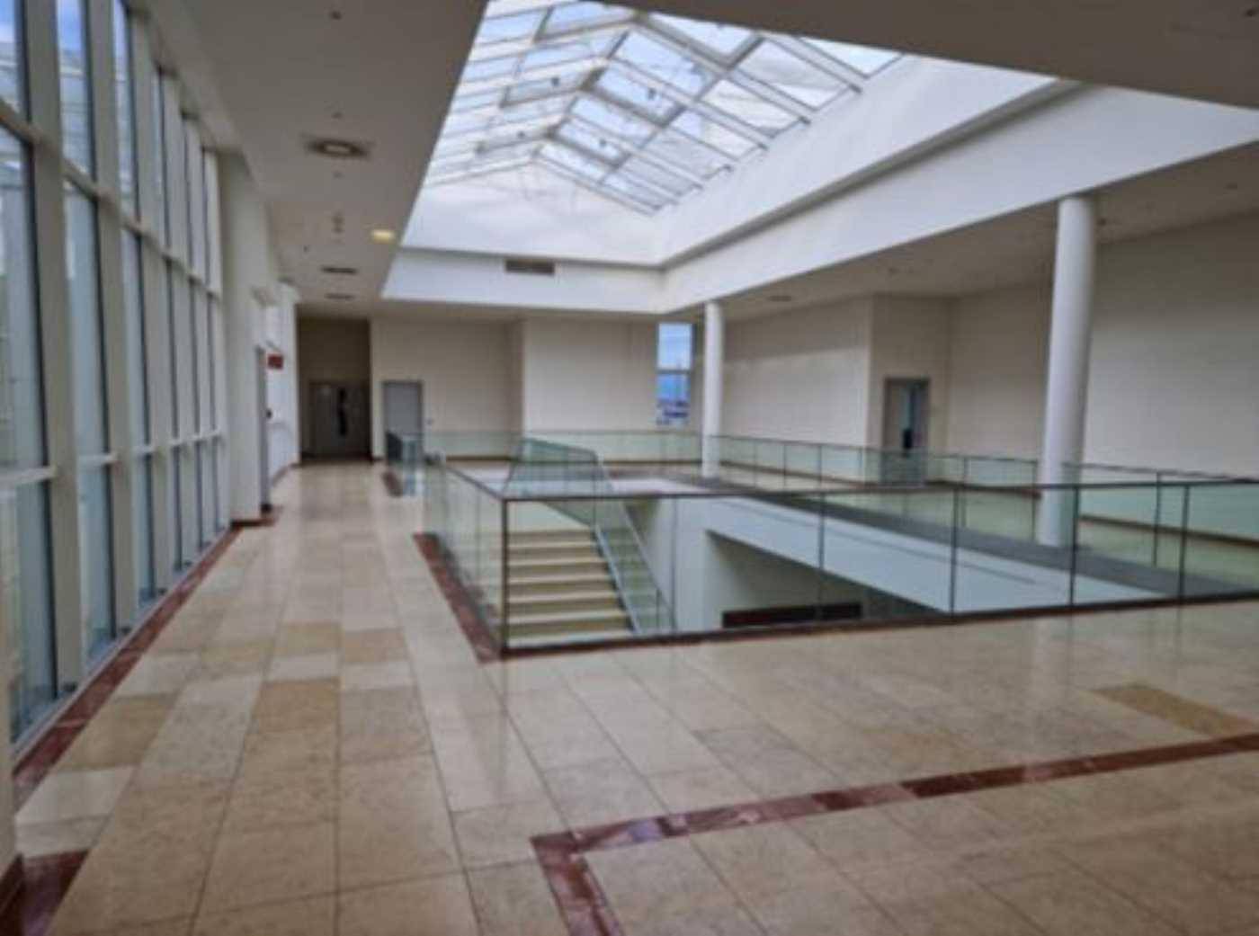 Heller Flur mit großem Oberlicht, Blick auf die untere Etage und eleganten Fliesenböden.