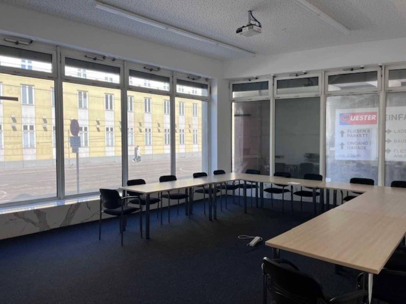Großer Konferenzraum mit U-förmiger Tischordnung, Teppichboden und Blick auf die Straße.