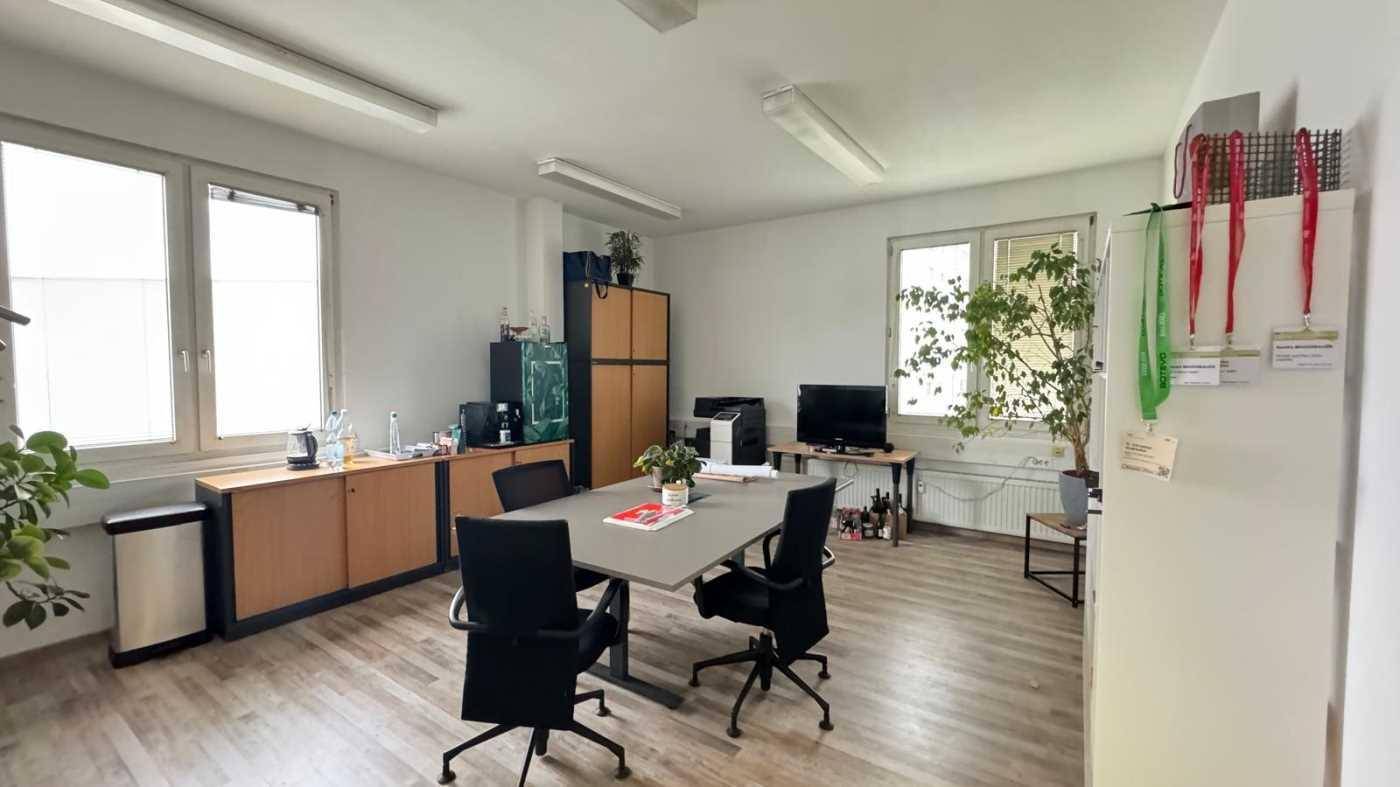 Geräumiges Büro mit Besprechungstisch, Holzfußboden und mehreren Fenstern.