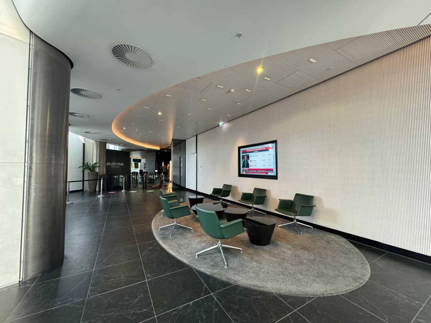 Moderne Hotellobby oder Empfangsbereich mit dunklem Fliesenboden und grünen Sitzgelegenheiten.