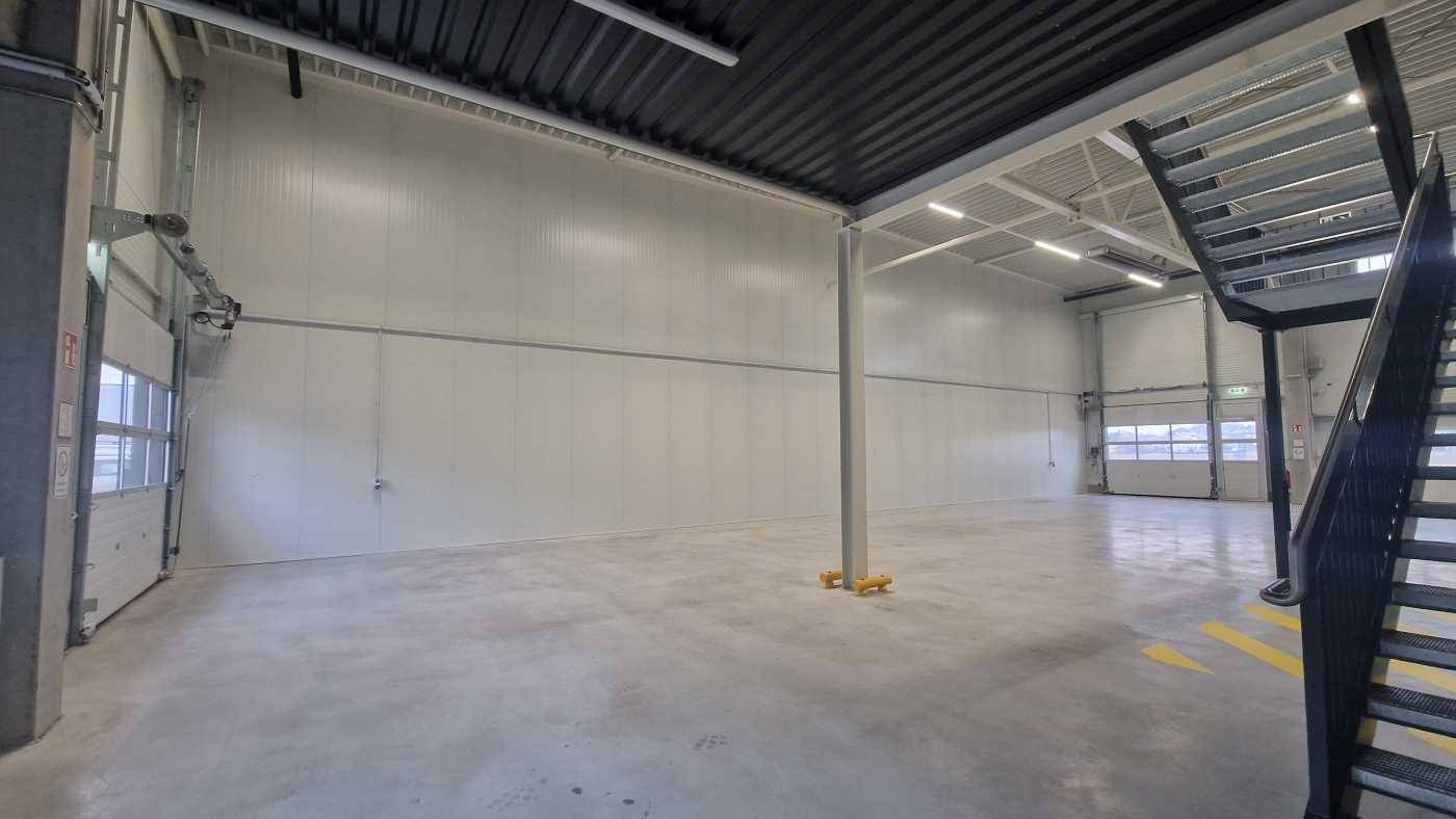 Heller und sauberer Industrieraum mit hohen Decken, Betonboden und einem zentralen Stützpfeiler.
