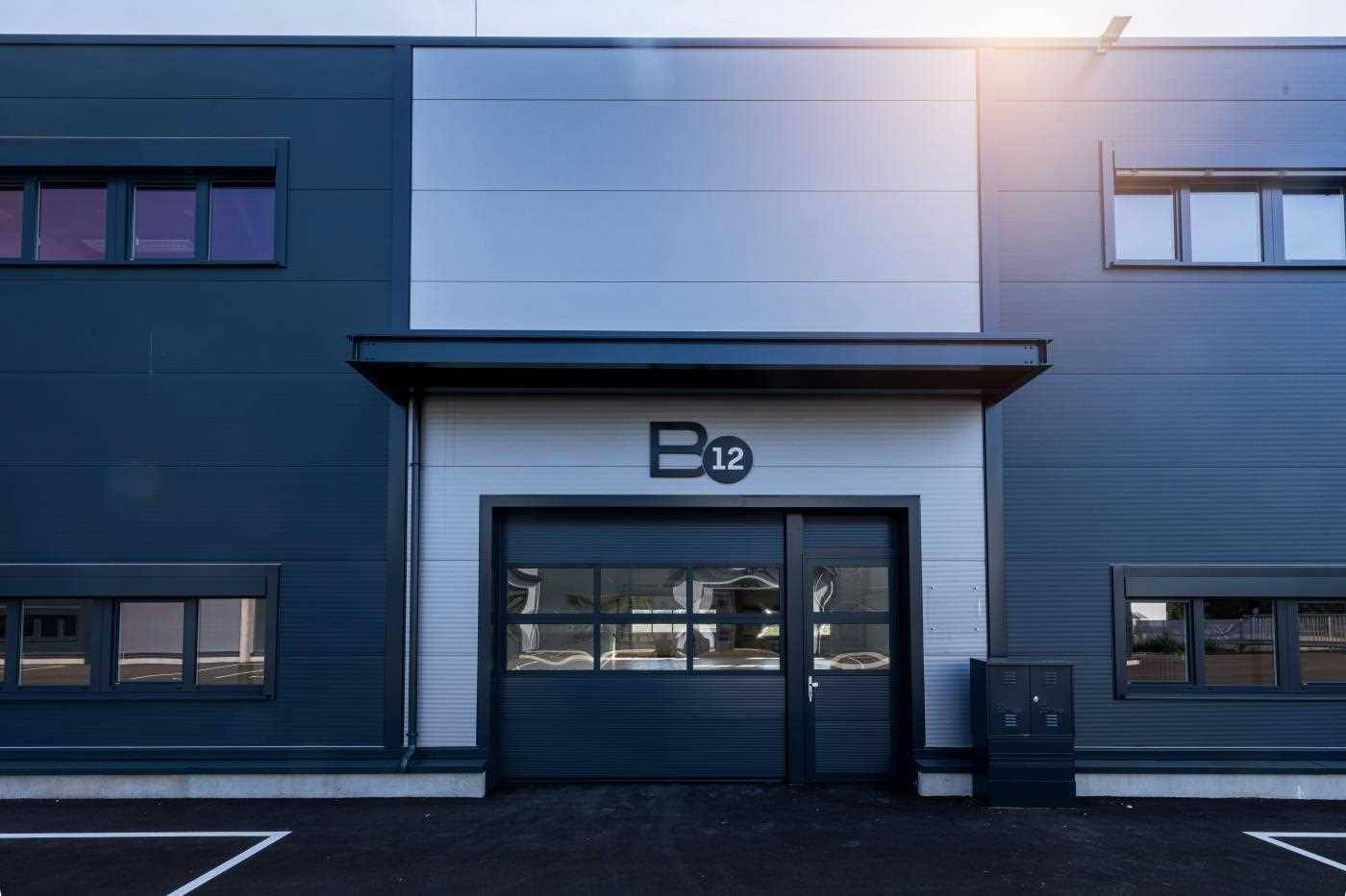 Moderne Gebäudefassade mit Rolltor und Eingangstür, gekennzeichnet mit der Nummer B12.