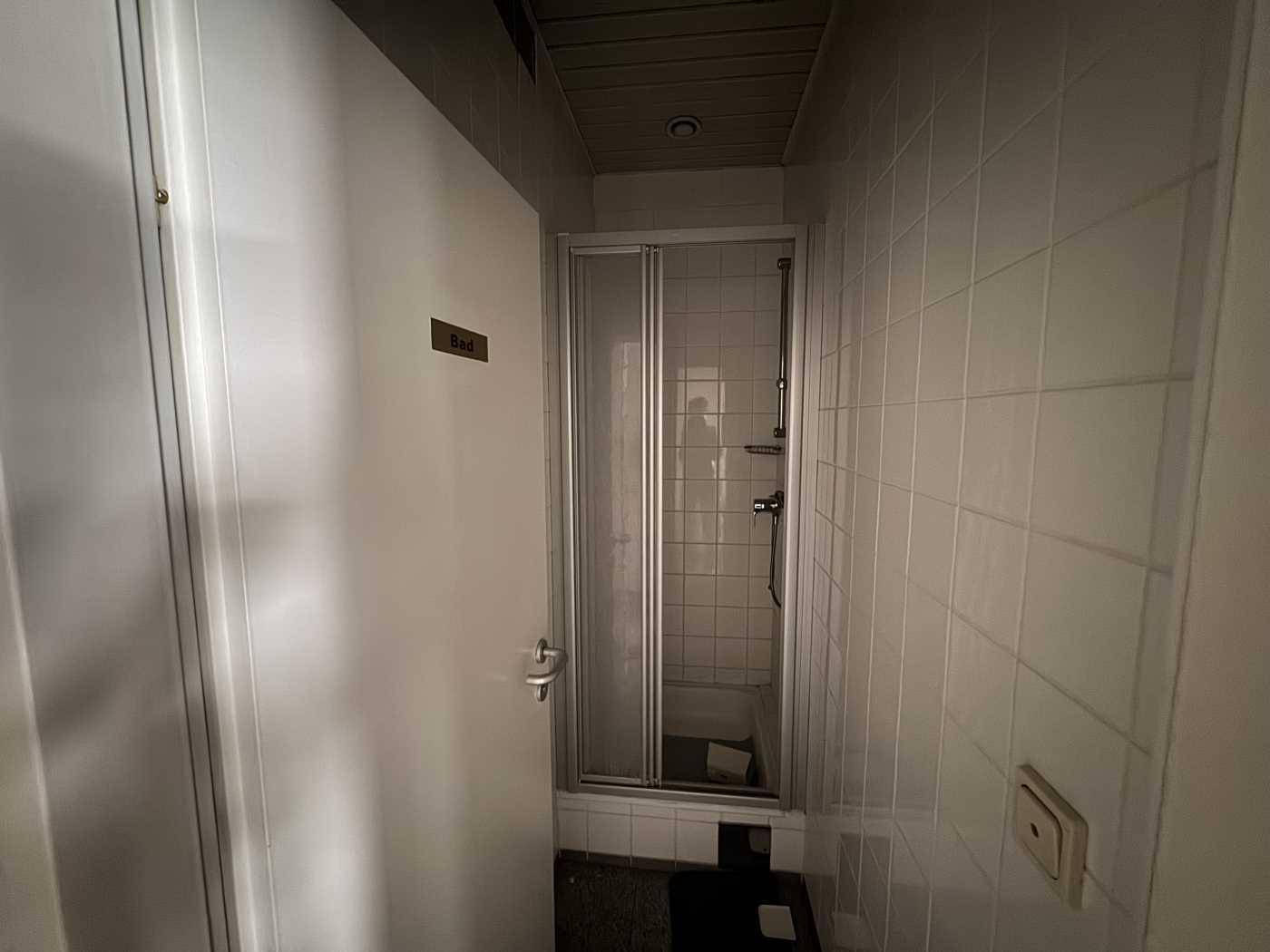 Kleines Badezimmer mit Duschkabine und weißen Fliesen, funktional und kompakt gestaltet.