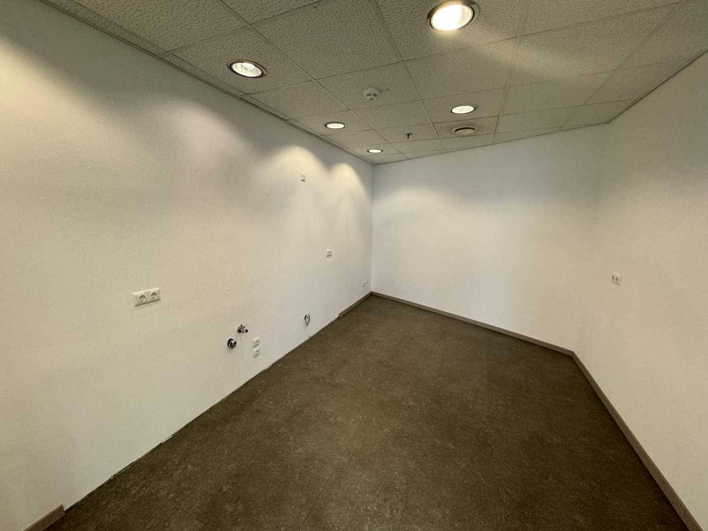 Kleiner, leerer Raum mit dunklem Boden und weißen Wänden, geeignet als Abstellraum oder kleine Teeküche.