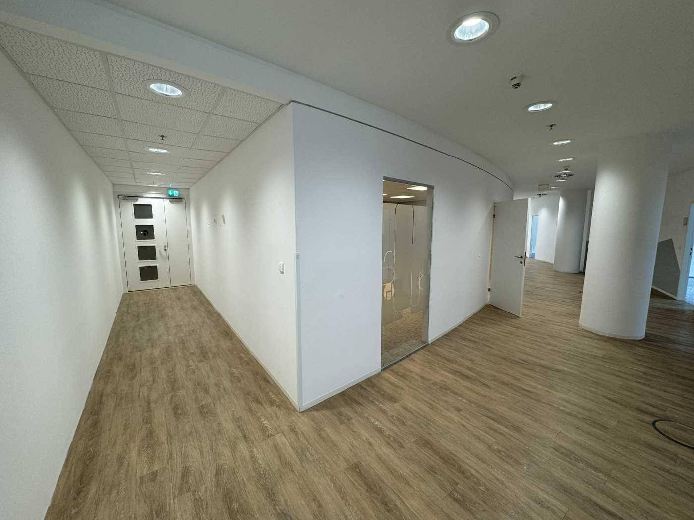 Heller Flur mit modernem Vinylboden in Holzoptik und weißen Wänden, der zu weiteren Räumen führt.