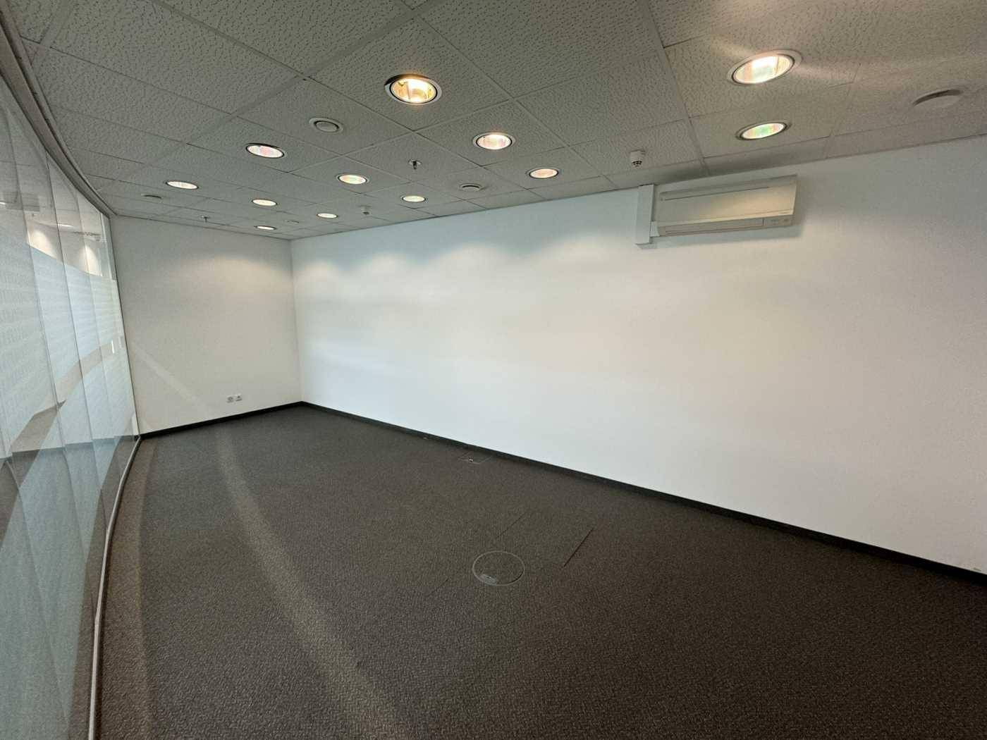 Kleiner Büroraum mit Teppichboden, weißen Wänden und einer Klimaanlage für individuellen Komfort.