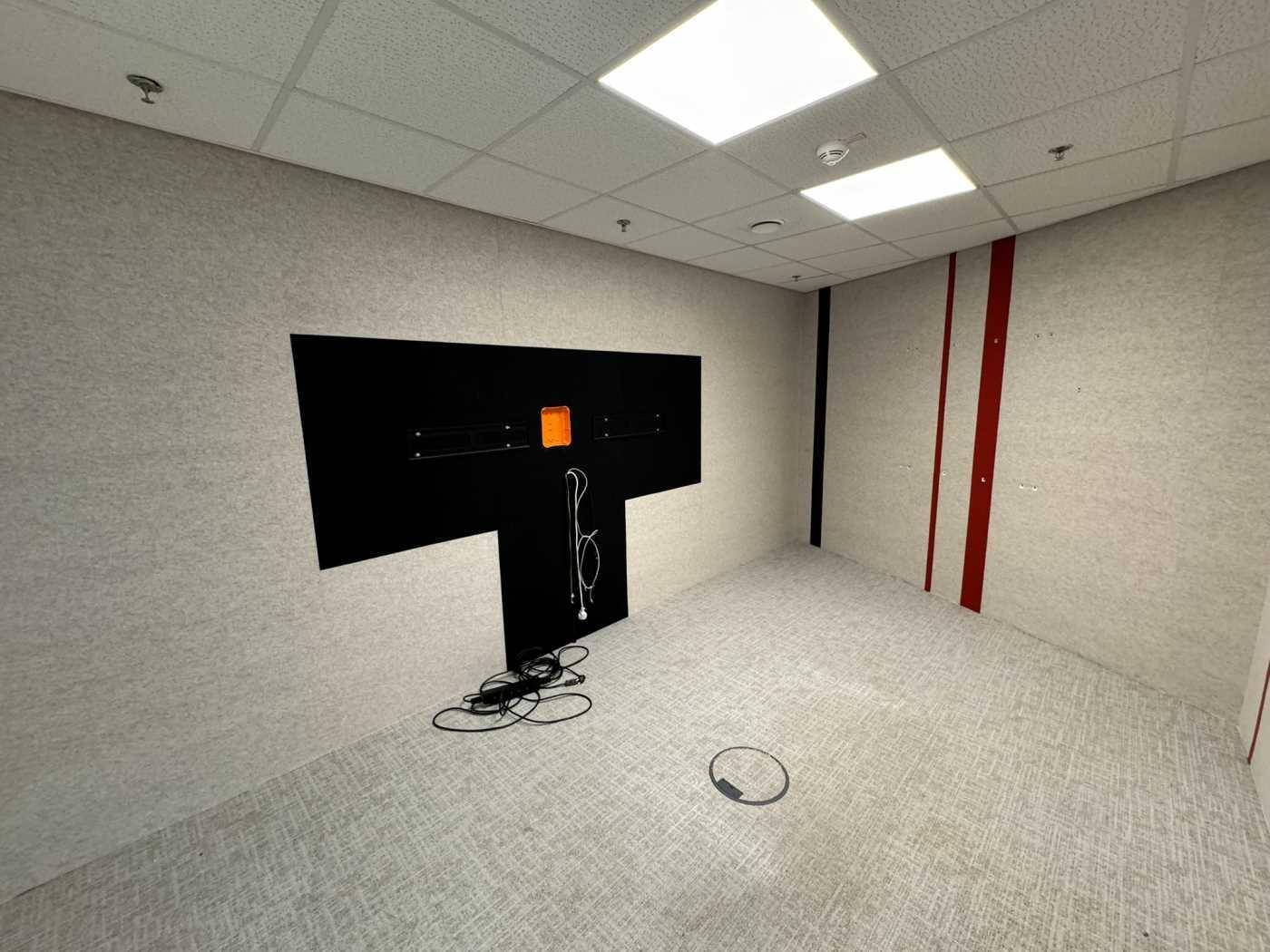 Büroraum mit Teppichboden und einer vorbereiteten Wand für einen Bildschirm, ideal für Präsentationen.