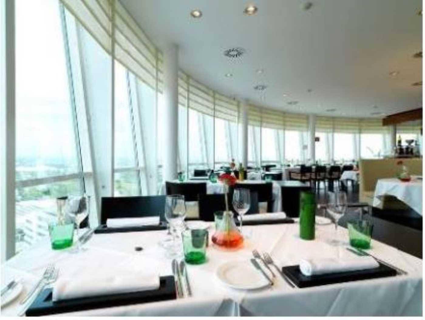 Elegantes Restaurant mit runden Tischen, Panoramablick und großen Fenstern, die viel Licht hereinlassen.