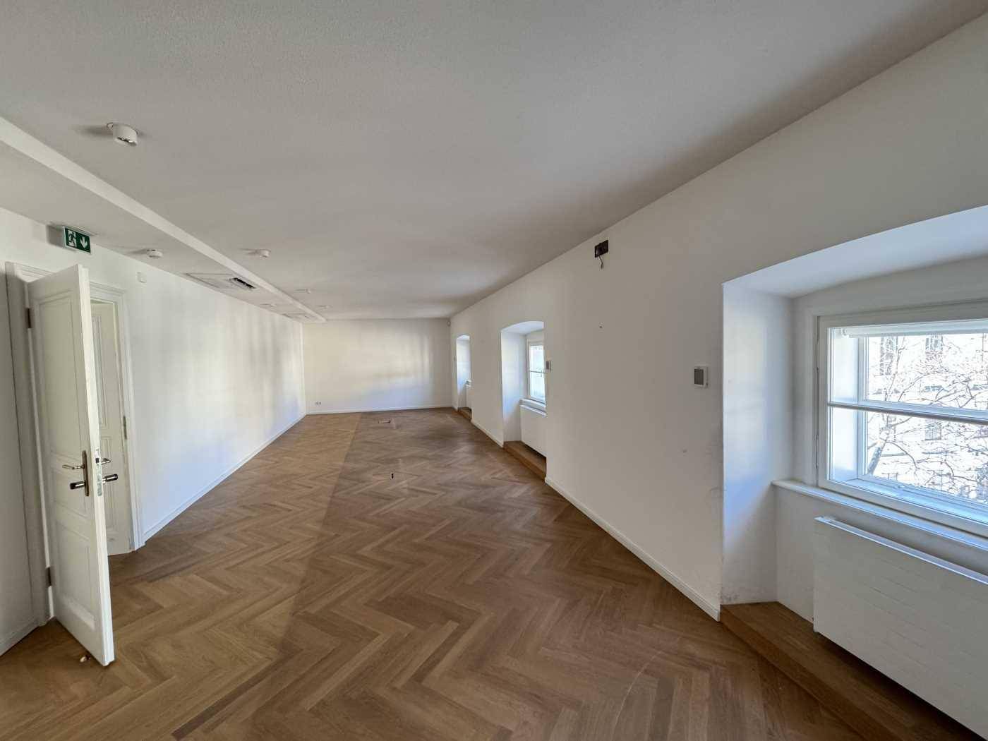 Langer, heller Raum mit Fischgrätparkett und mehreren Fenstern, ideal für flexible Bürolösungen.