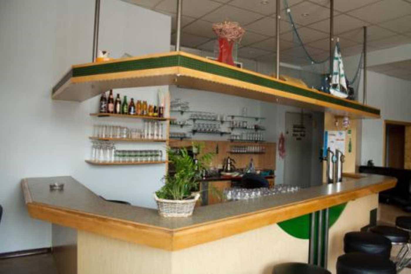 Gemütliche Bar mit Holztheke, Regalen für Gläser und Flaschen sowie Hockern.