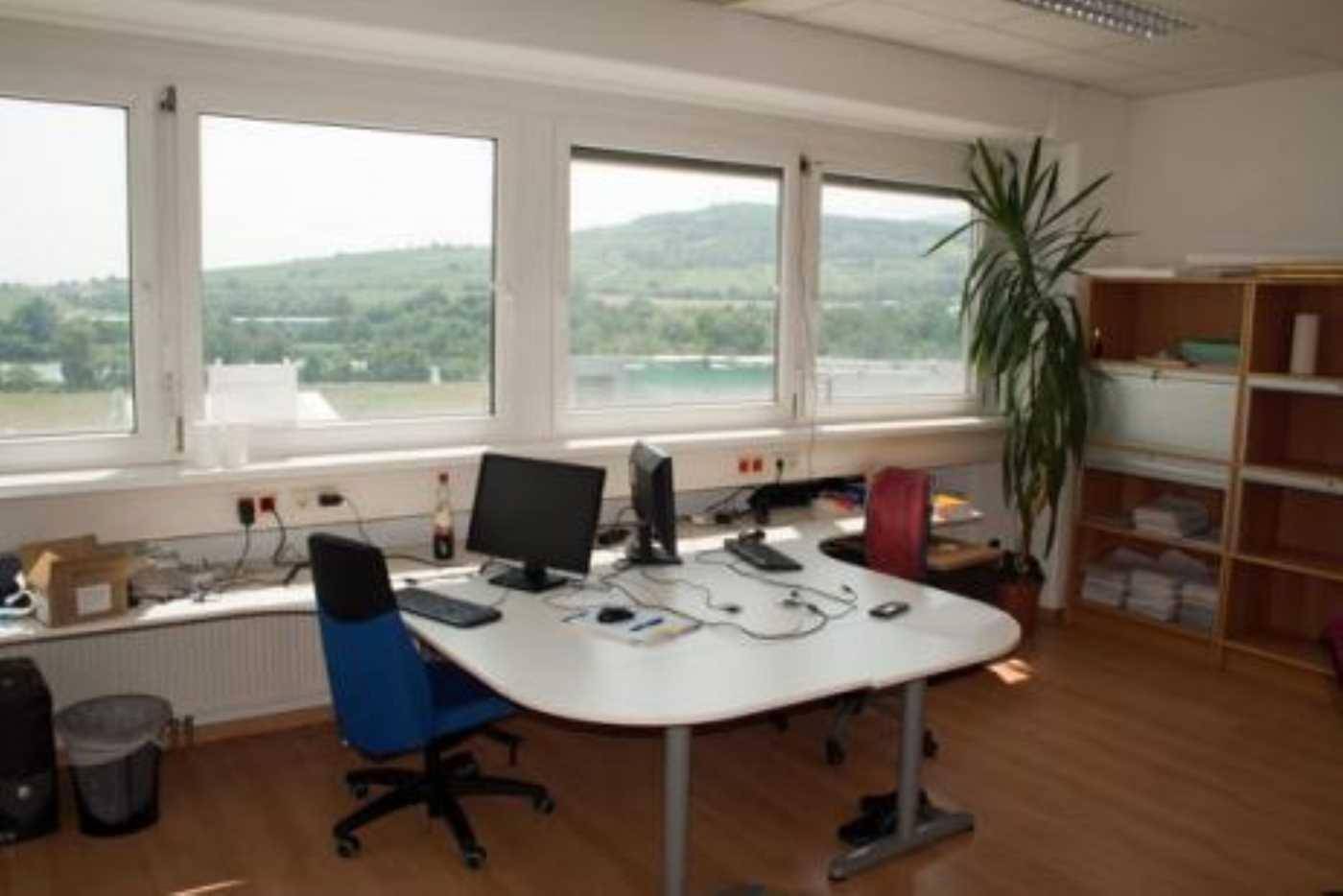 Helles Büro mit Holzboden, Schreibtischen und einem weiten Blick auf die grüne Landschaft.